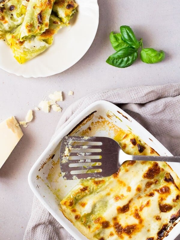 Homemade basil pesto is spread over fresh cannelloni pasta recipe and baked in a luscious cheesy provolone bechamel sauce and topped with mozzarella cheese, comfort food heaven! Insidetherustickitchen.com