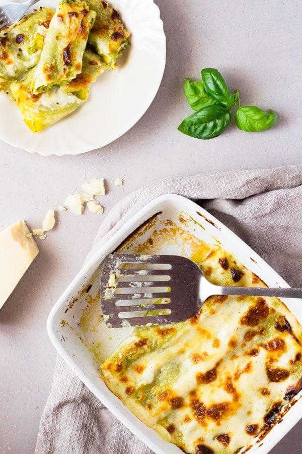 Homemade basil pesto is spread over fresh cannelloni pasta recipe and baked in a luscious cheesy provolone bechamel sauce and topped with mozzarella cheese, comfort food heaven! Insidetherustickitchen.com pesto-provolone-cannelloni-pasta-insidetherustickitchen