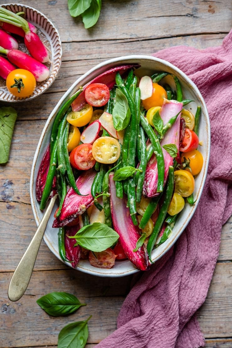 An overhead shot of a green bean salad in a rustic serving bowl