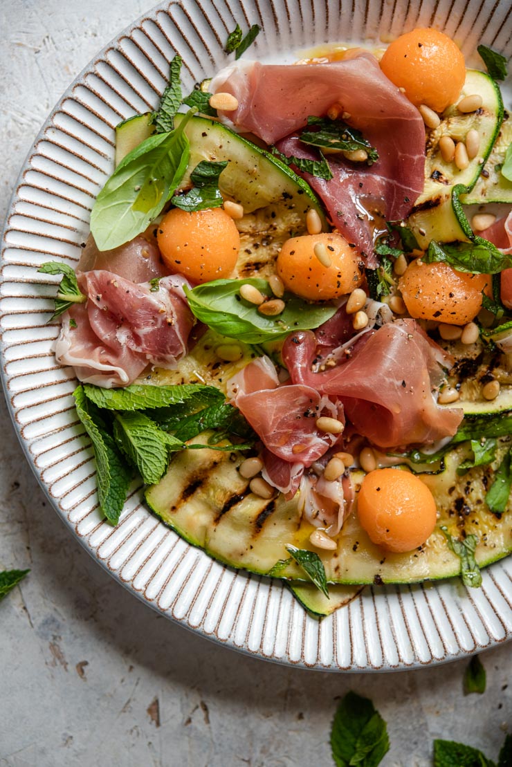 An overhead shot of a zucchini salad with melon and prosciutto