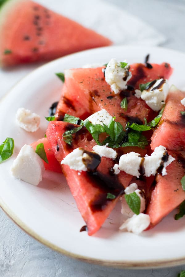 A delicious light watermelon basil salad with mint, goats and balsamic glaze. Refreshing and healthy salad recipe insidetherustickitchen