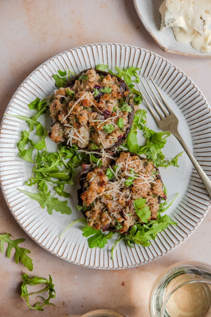 An overhead shot of sausage stuffed mushrooms on a rustic plate