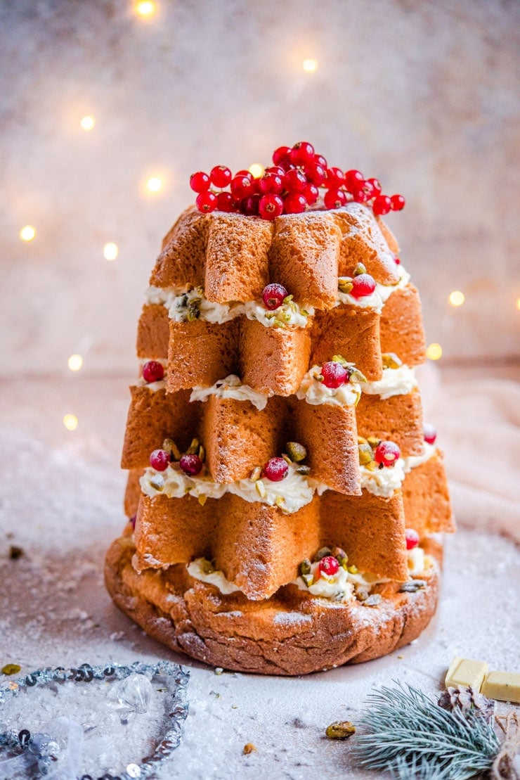 A pandoro christmas tree cake topped with fairy lights in the background