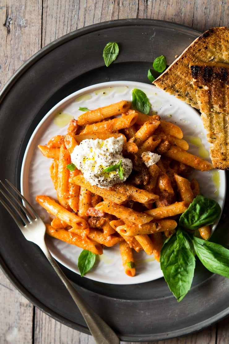 pasta with pancetta on a plate with ricotta and basil