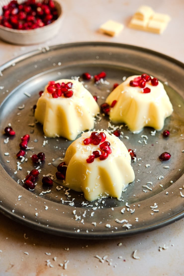 White chocolate panna cotta on a serving plate with pomegranate