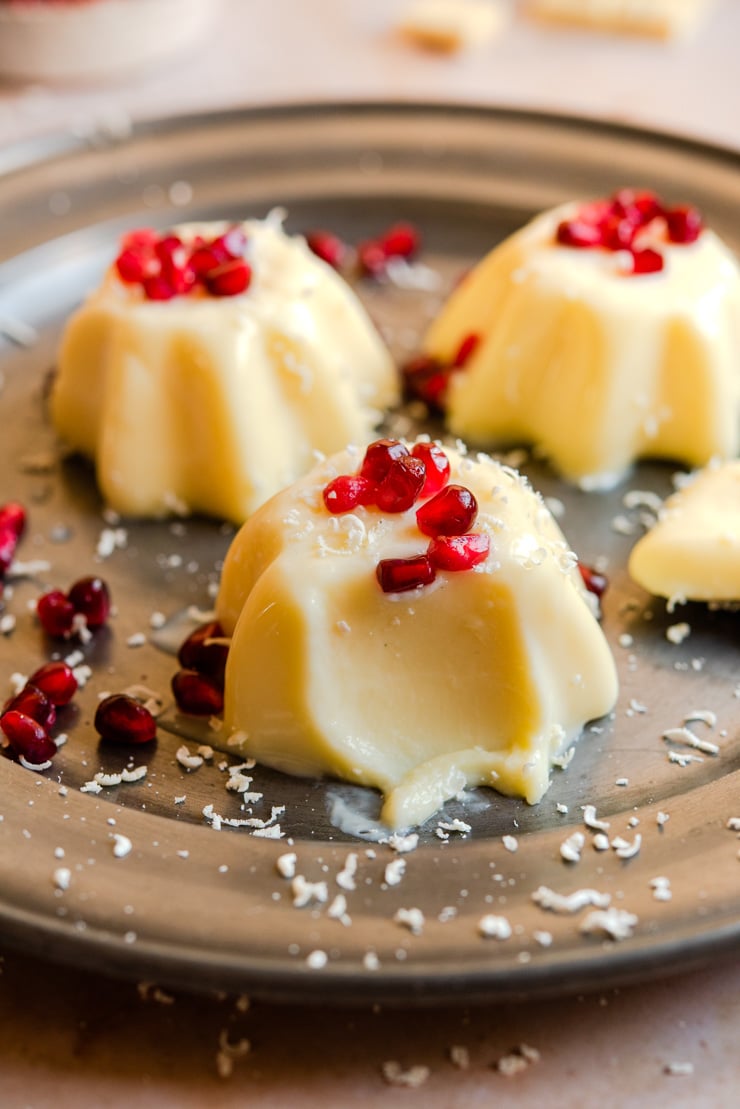 A close up of white chocolate panna cotta with a bite out on a plate