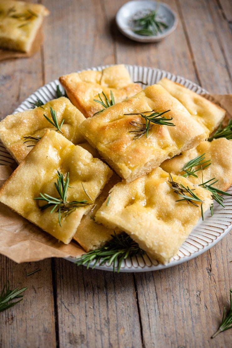 A side shot of rosemary focaccia cut into squares on a rustic plate