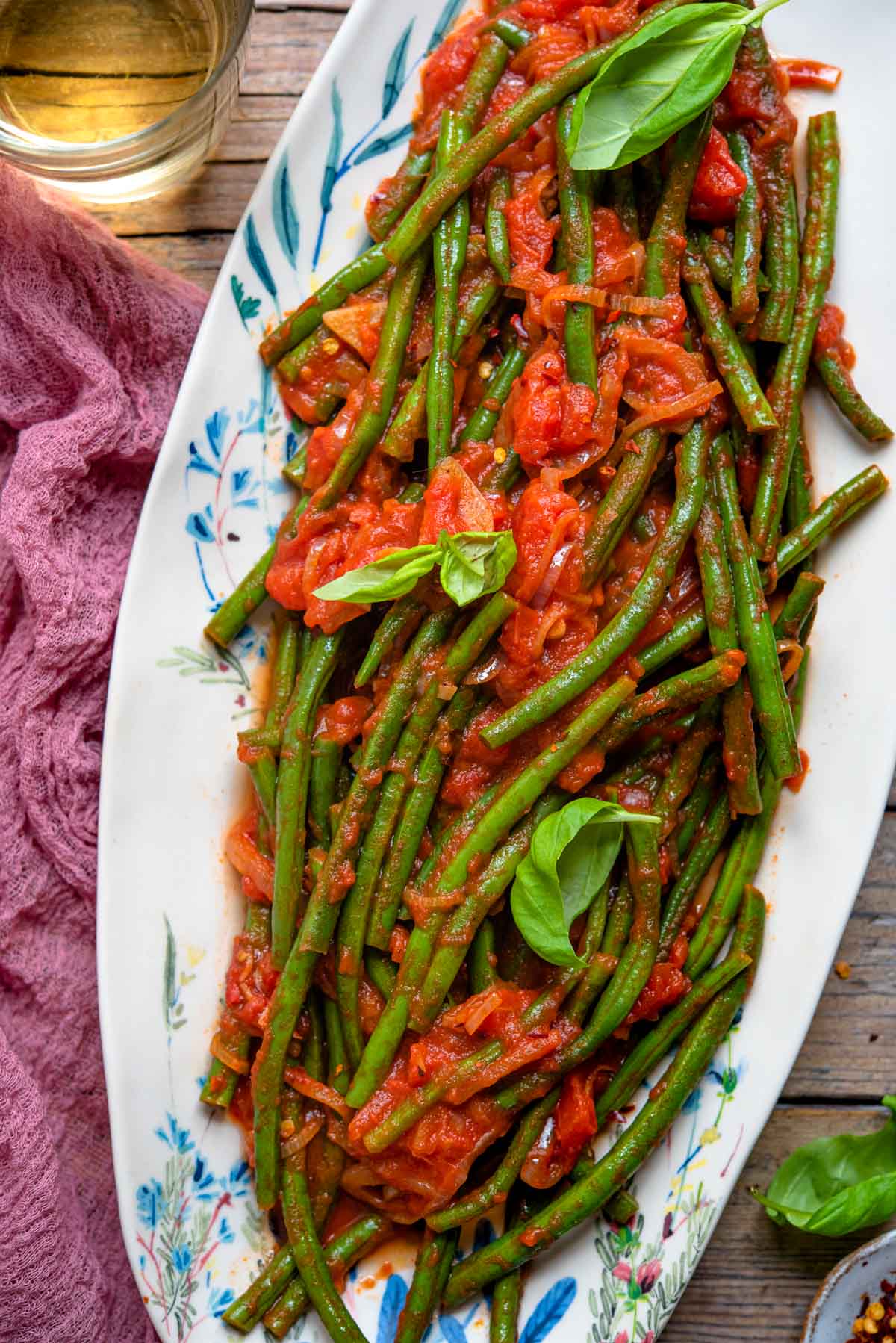 A close up of Italian green beans in tomato sauce on a oval plate