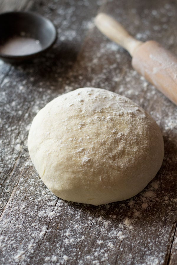 Yeast free pizza dough on a wooden surface with flour at the side