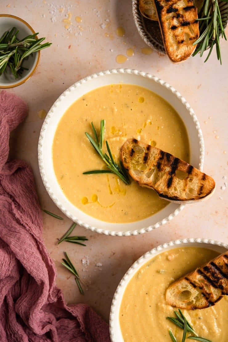 Chickpea soup in a bowl topped with crusty ciabatta and rosemary