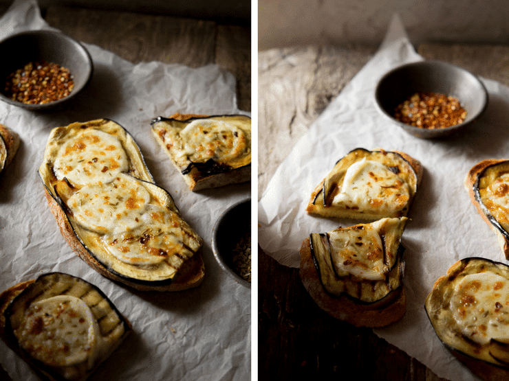 A close up of eggplant bruschetta with mozzarella sitting on crushed baking paper on a wooden surface