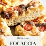 A close up of a slice of tomato and anchovy focaccia with green text at the bottom that says 'Focaccia - Tomato & Anchovy. Get the recipe.'