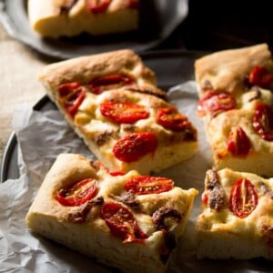 Cherry tomato focaccia with anchovies cut into slices sitting on a rustic plate