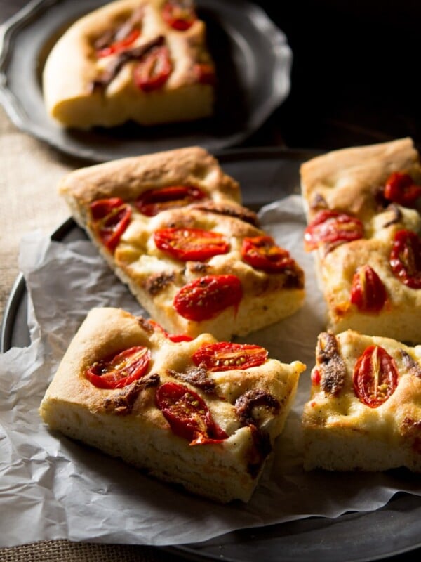 Cherry tomato focaccia with anchovies cut into slices sitting on a rustic plate