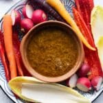 Bagna Cauda in a terracotta dish with raw vegetables all around.