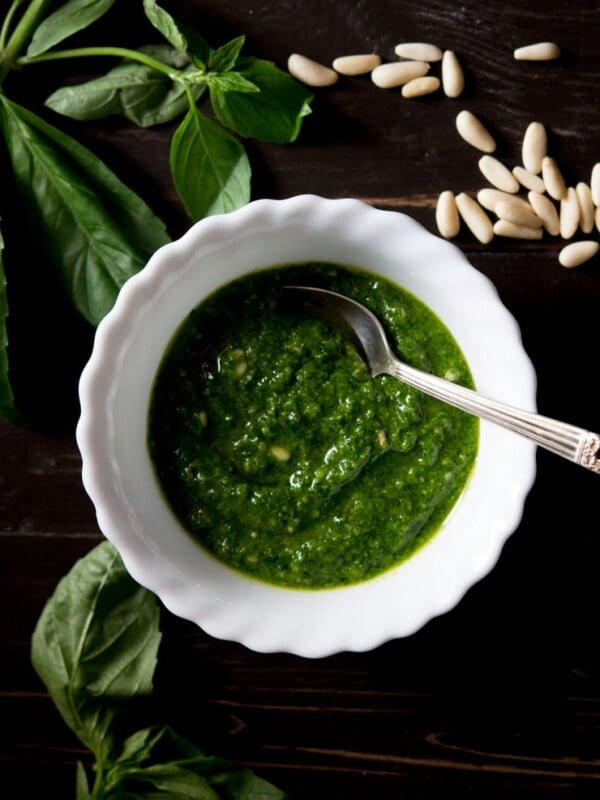 Recipe for how to make basil pesto, pesto in a bowl with basil and pine nuts
