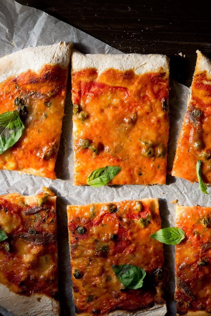 An overhead close up of anchovy pizza with capers cut into slices