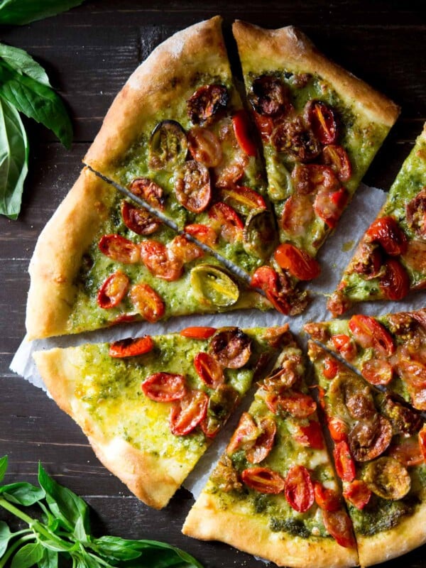 An overhead shot of a basil pesto pizza cut into slices