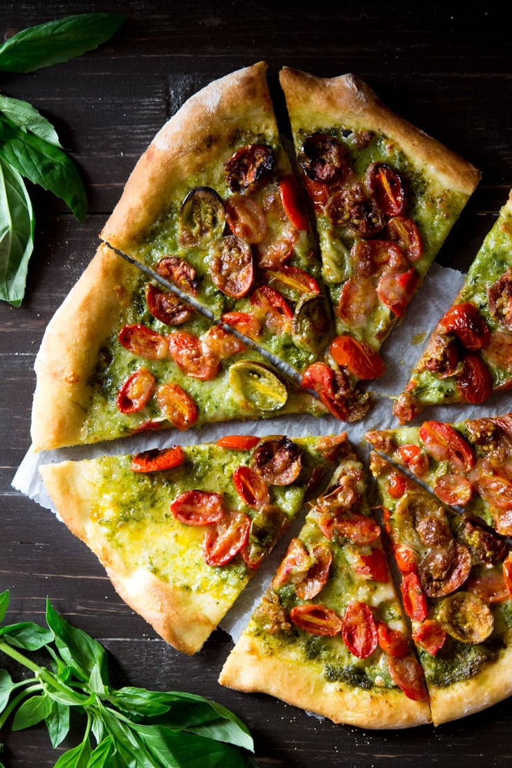 basil pesto pizza topped the cherry tomatoes and mozzarella cut into slices on a wooden board with basil 