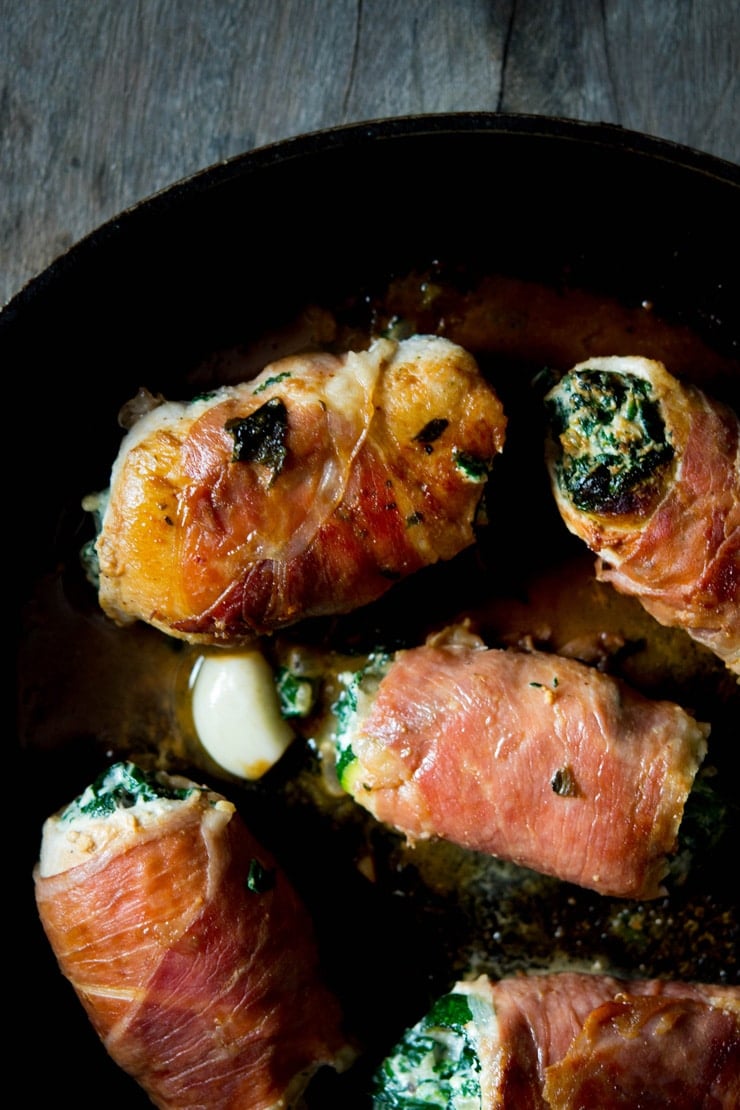 A close up of chicken involtini in a pan stuffed with spinach and ricotta