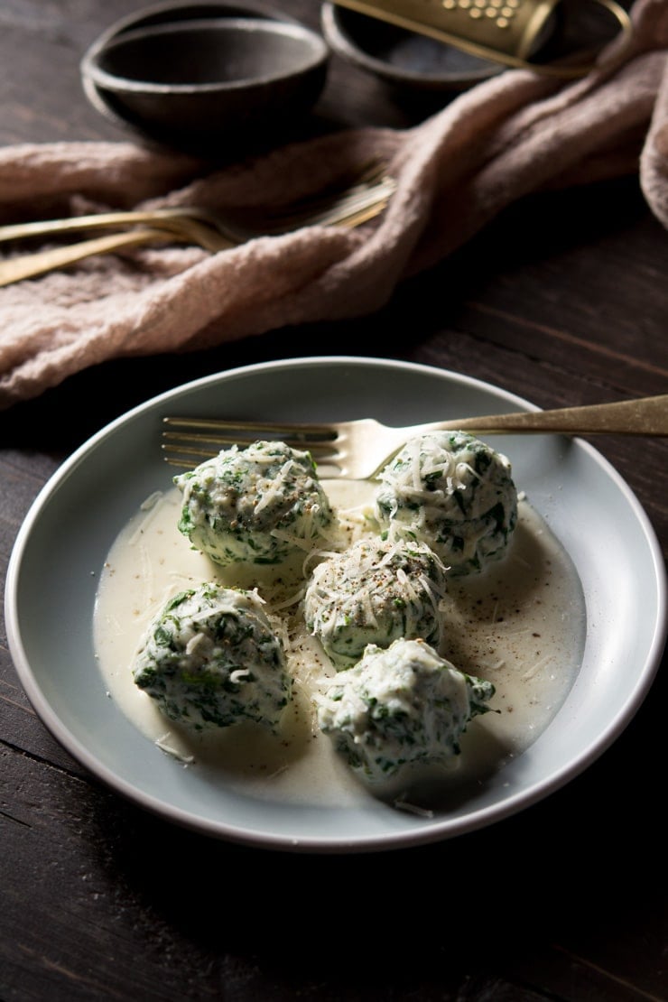 Broccoli rabe and ricotta gnudi on a blue plate with parmesan cream