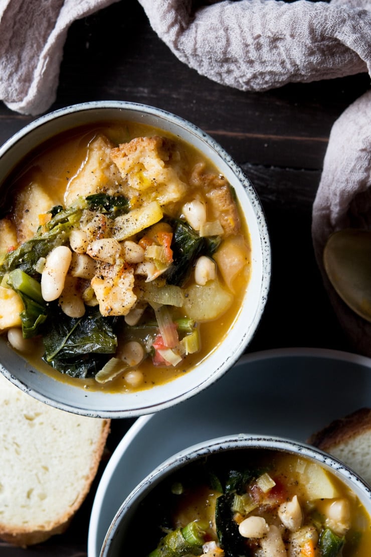 Overhead shot of ribollita Tuscan vegetable stew with bread in background