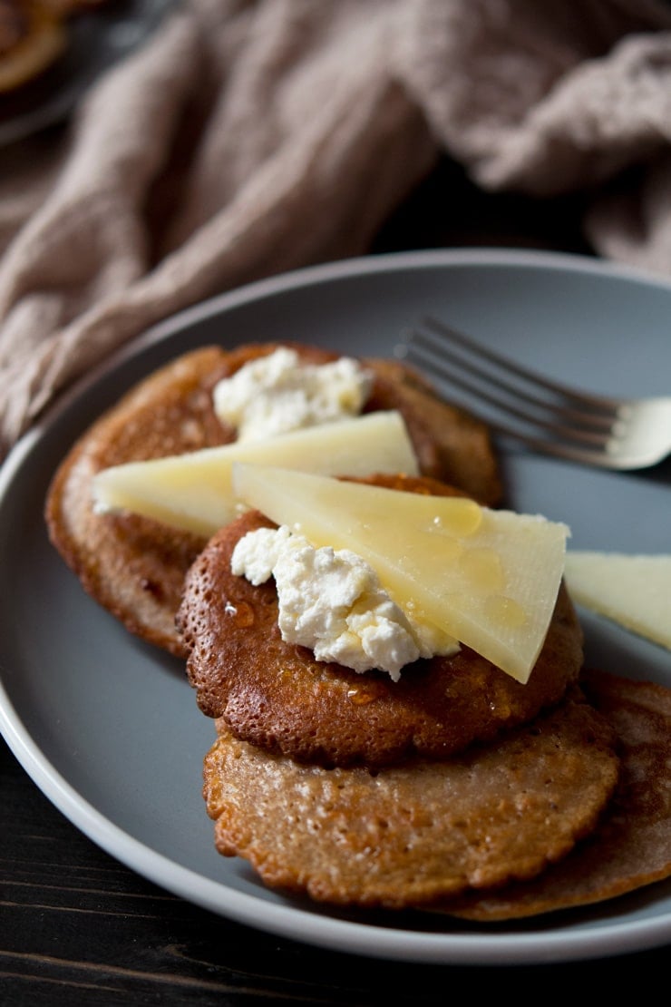 a close up of chestnut fritters topped with pecorino cheese, ricotta and honey