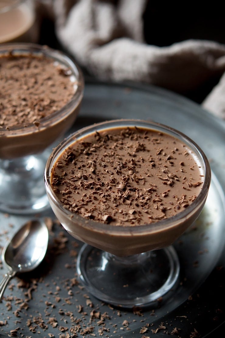 Close up of chocolate panna cotta in a glass bowl topped with grated chocolate.