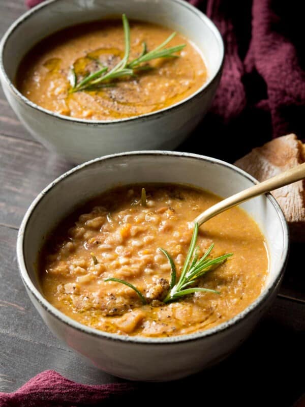 Tuscan farro soup in a bowl with a spoon and rosemary