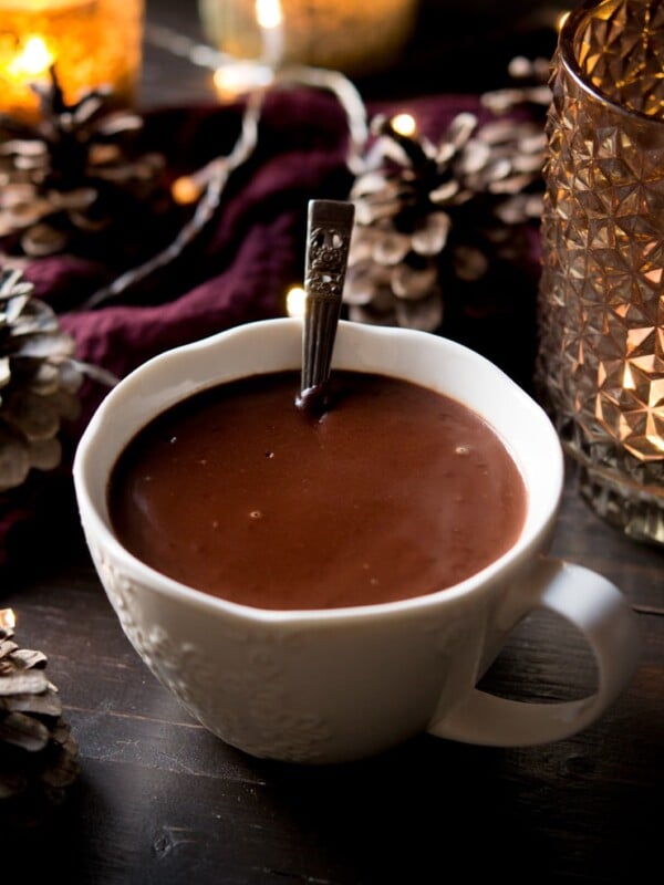 A white mug filled with Italian hot chocolate with a metal spoon in it.