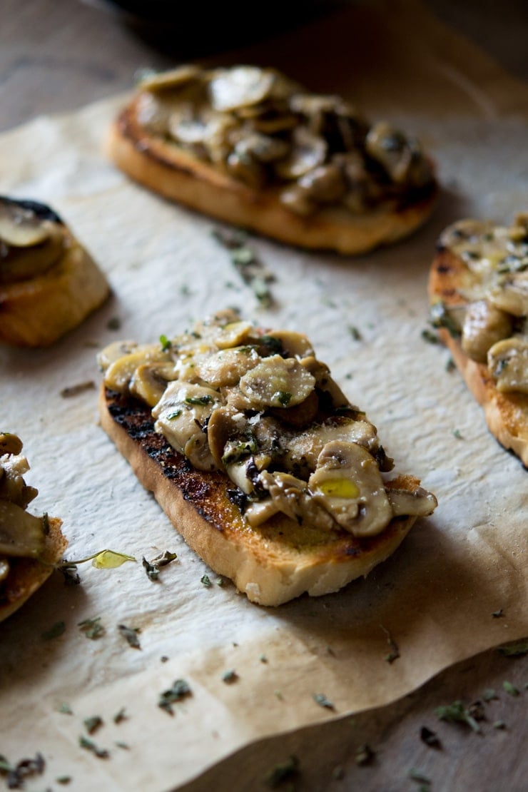 Mushroom toasts on a sheet of baking paper drizzled with olive oil