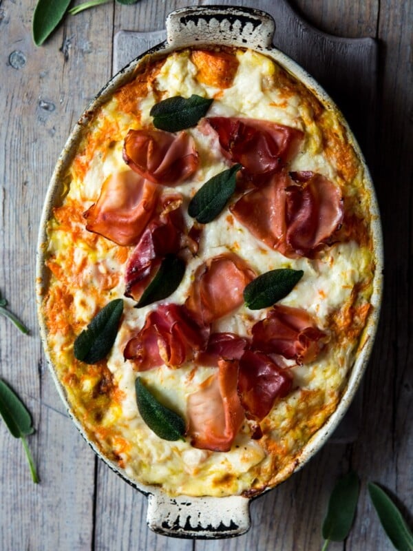butternut squash lasagna in an oval baking dish on a wooden surface