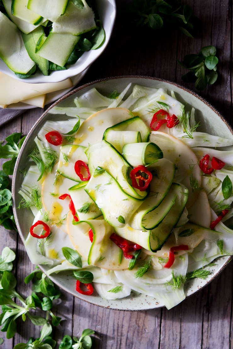 an overhead shot of courgette salad with fennel and smoked scamorza cheese on a large plate
