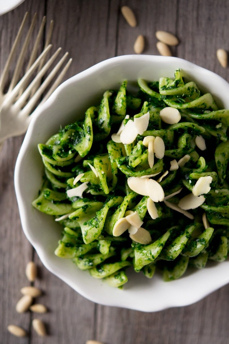 A close up of pesto pasta sauce with fusilli pasta in a white bowl