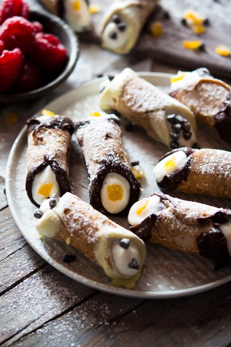 A close up of mini cannoli with chocolate chips on a plate