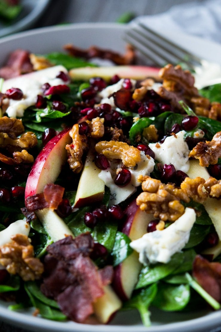 a close of a winter salad made with apple, spinach, pomegranate and gorgonzola