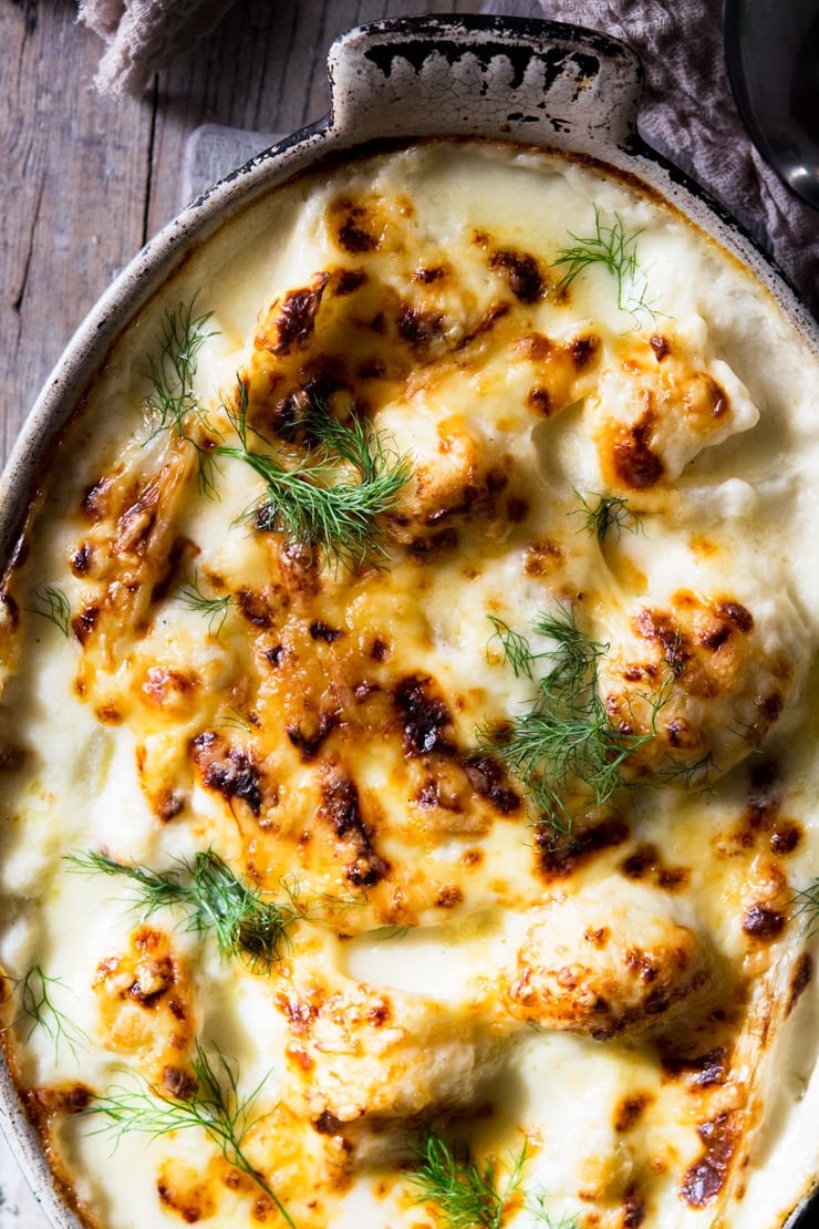 A close up golden melted cheese on top of baked cauliflower cheese