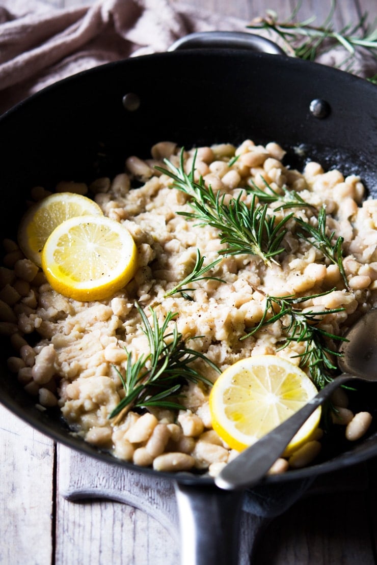 Cannellini bean mash in a large pan with lemon and rosemary