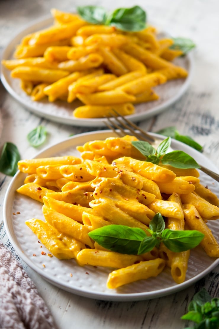 A close up of butternut squash pasta on a plate with basil