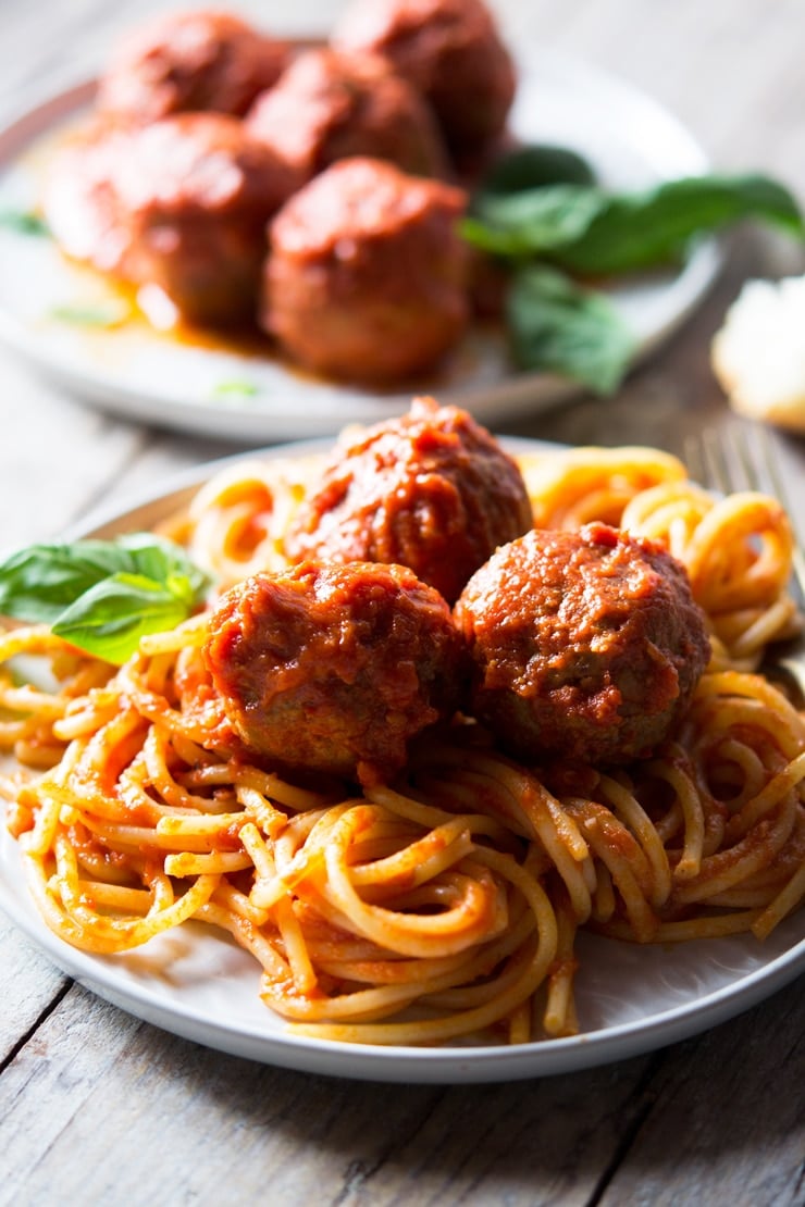 Three mozzarella stuffed meatballs on a plate of spaghetti