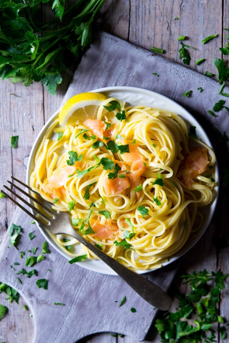 An overhead shot of smoked salmon pasta on a plate with chopped parsley on top