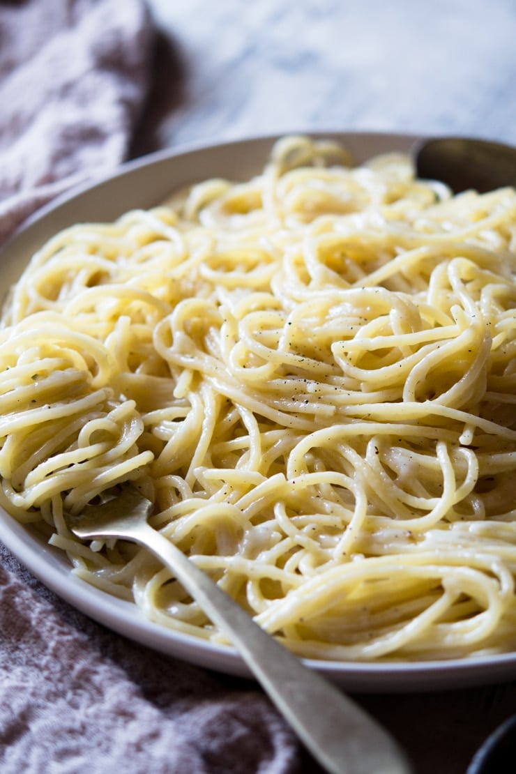 A side shot of a cacio e pepe recipe on a plate with a fork