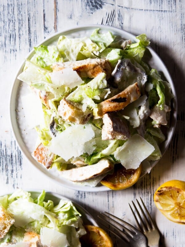 an overhead shot of a grilled chicken caesar salad on a wooden surface