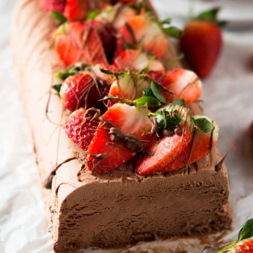 A chocolate semifreddo recipe on a white surface topped with fresh berries