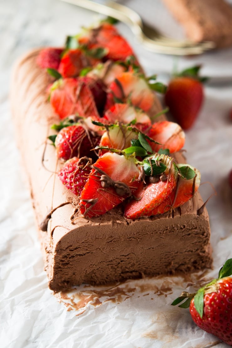 A chocolate semifreddo recipe on a white surface topped with fresh berries