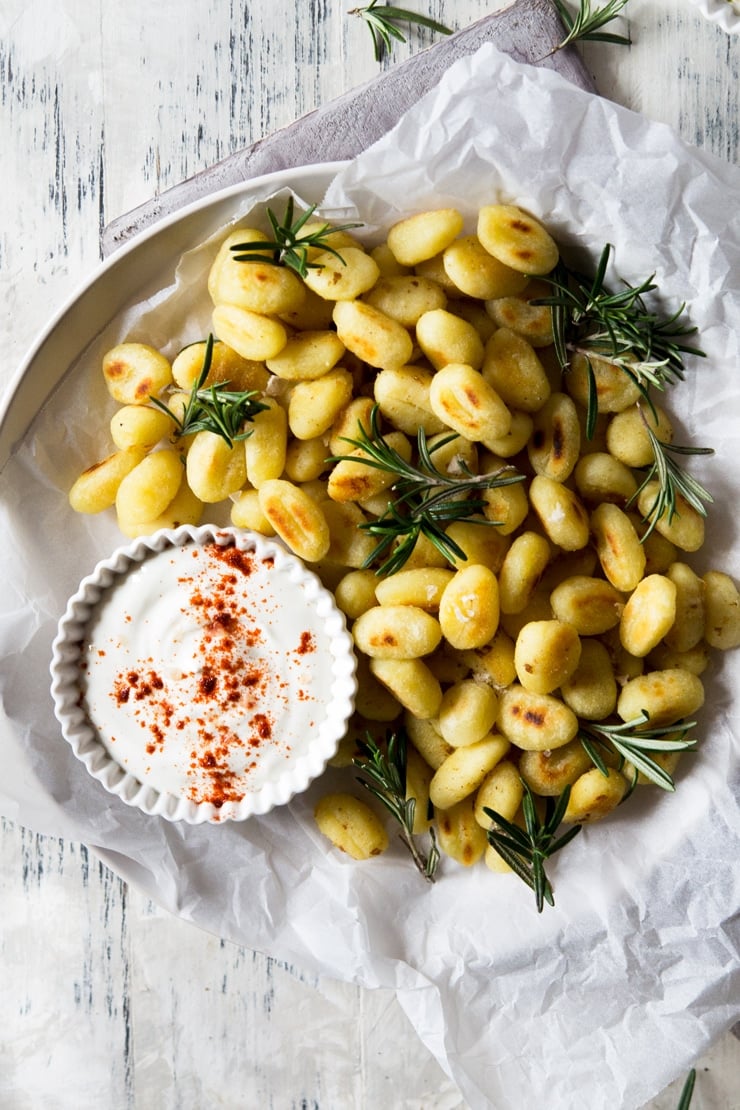 An overhead shot of fried gnocchi on a plate with a dip on the side