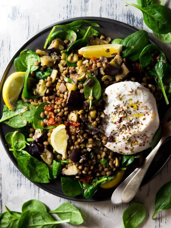 a loaded lentil salad on a pewter plate topped with burrata cheese