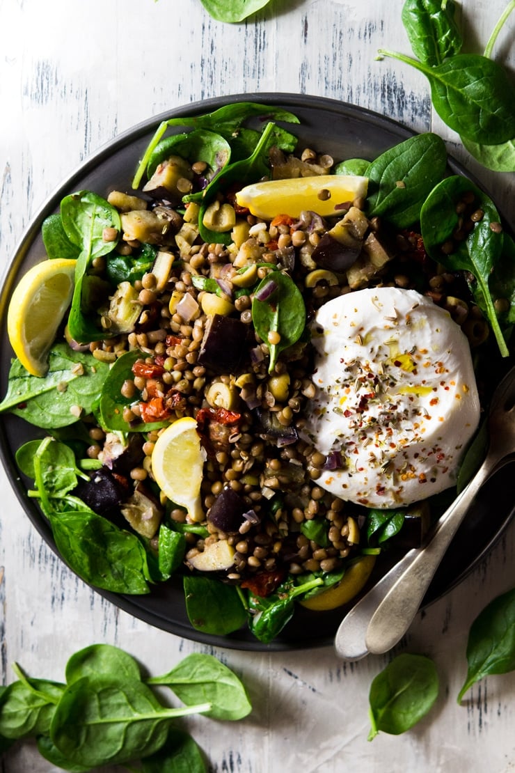 An overhead shot of an Italian lentil salad with eggplant and burrata cheese on a pewter plate