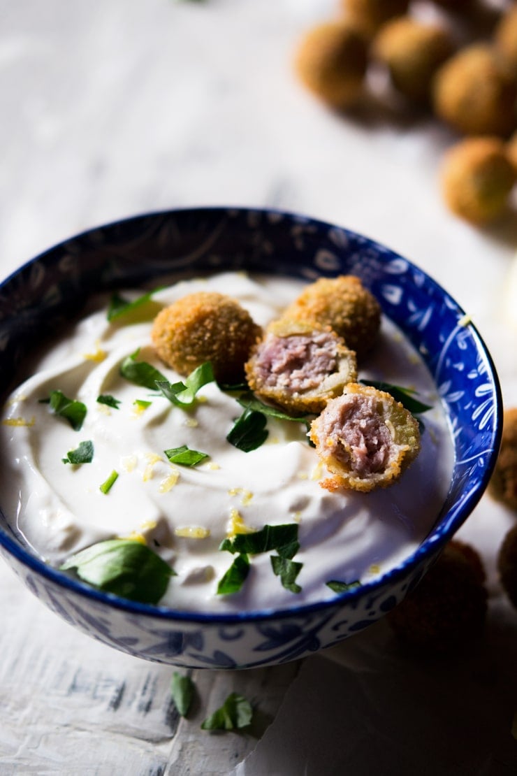 Sausage stuffed olives cut in half and placed on top of a sour cream dip