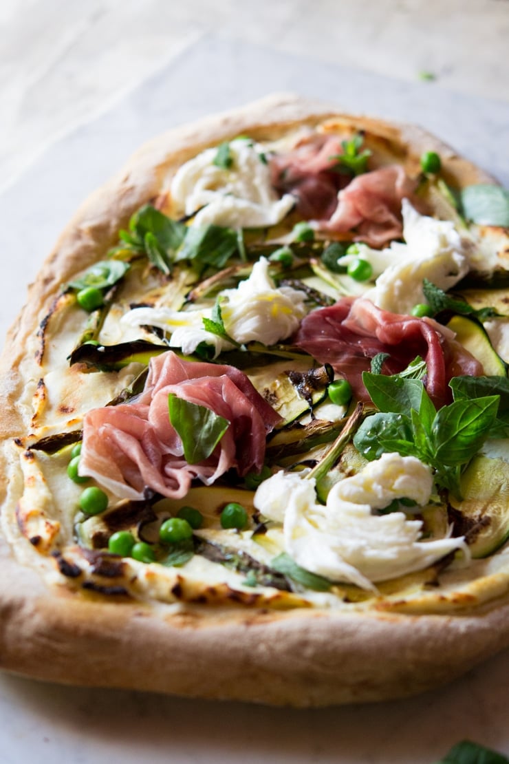 A close up of pizza with zucchini, asparagus and prosciutto